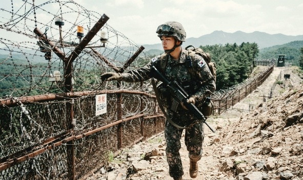 군인이 철책선을 짜라 걸으며 철책을 점검하고 있다